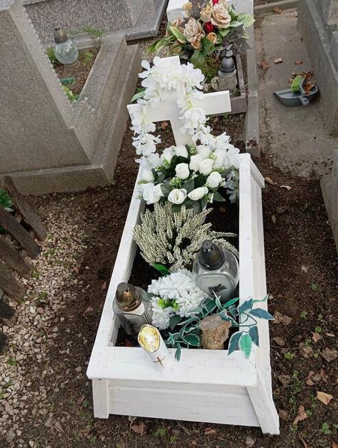 Tymczasowa obudowa nagrobka dla dziecka z krzyżem.