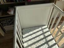 drewniane białe łóżeczko z materacem