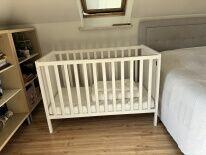 drewniane białe łóżeczko z materacem