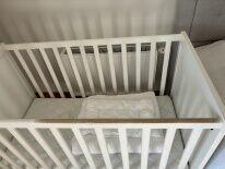 drewniane białe łóżeczko z materacem