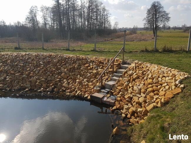 Kamień na skarpy brzegu stawu jeziora zbiornika wodnego