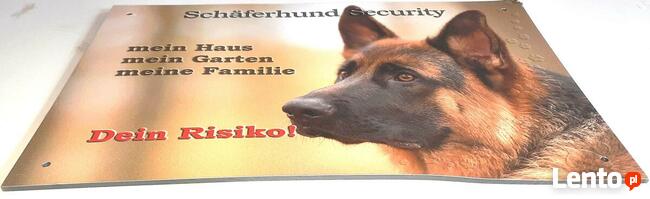 Tablica ostrzegawcza, informacyjna z owczarkiem niemieckim.