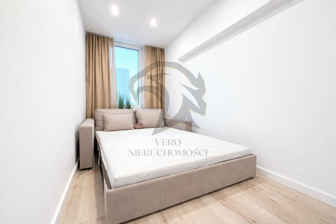 Wiesia w fartuchu w kratę stoi z wałkiem w ręku.