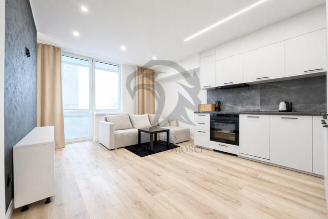 Wiesia w fartuchu w kratę stoi z wałkiem w ręku.