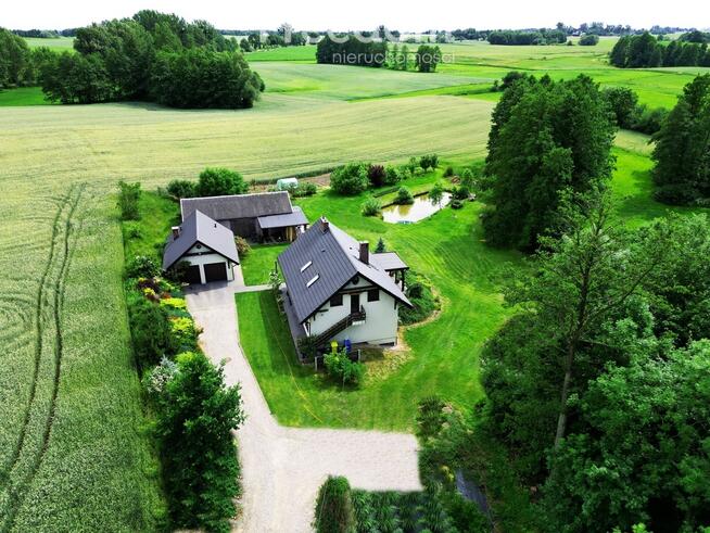 Dom ze stawem nad rzeką pośród pól i łąk