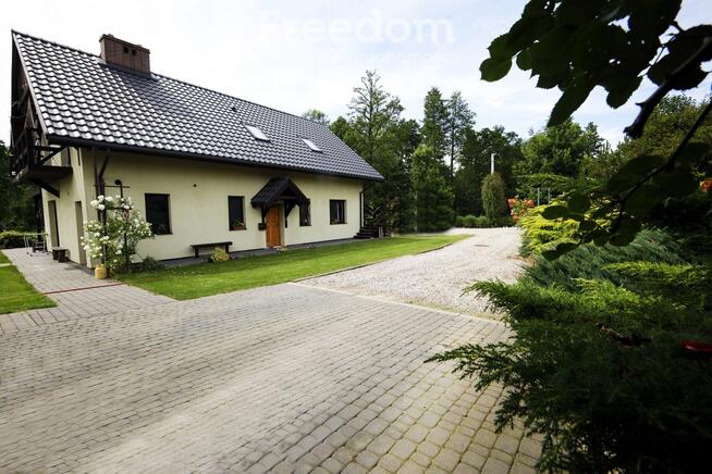 Dom ze stawem nad rzeką pośród pól i łąk