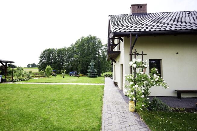 Dom ze stawem nad rzeką pośród pól i łąk