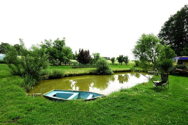 Dom ze stawem nad rzeką pośród pól i łąk