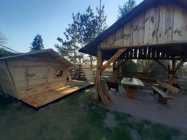 drewniany domek z kominkiem ogrodzony drewnianym płotem