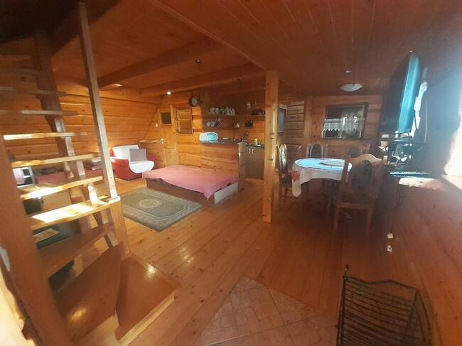 drewniany domek z kominkiem ogrodzony drewnianym płotem