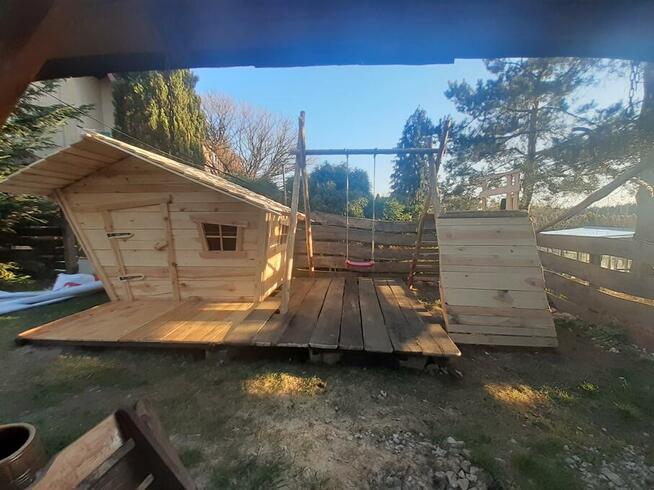 drewniany domek z kominkiem ogrodzony drewnianym płotem