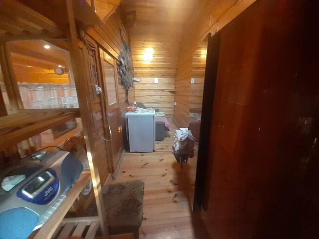 drewniany domek z kominkiem ogrodzony drewnianym płotem