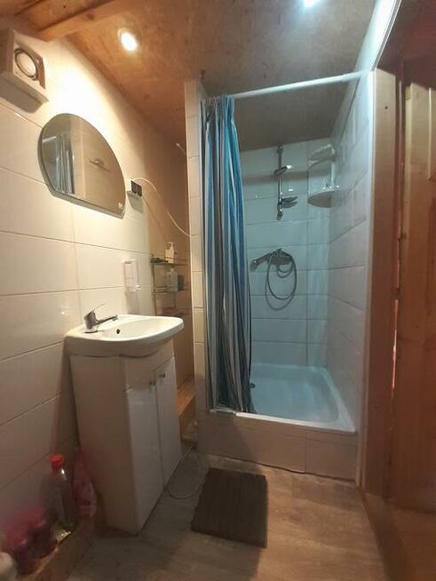 drewniany domek z kominkiem ogrodzony drewnianym płotem