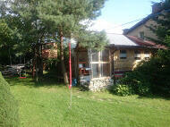 drewniany domek z kominkiem ogrodzony drewnianym płotem