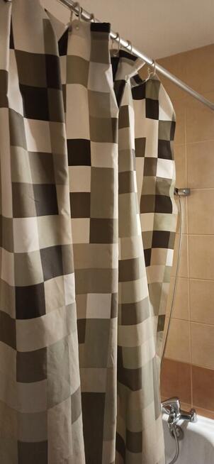 Drążek prysznicowy nad wanną z zasłoną.