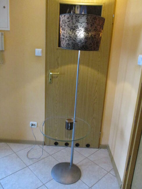 Lampa stojąca z półką szklaną.
