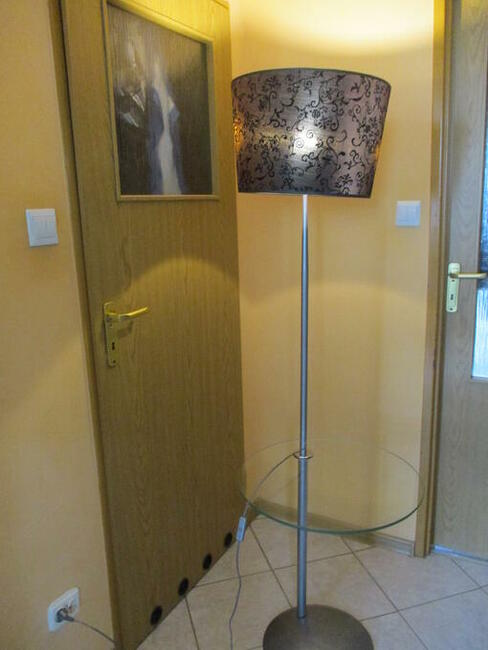 Lampa stojąca z półką szklaną.