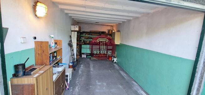 Funkcjonalny garaż z regałami i oświetleniem.