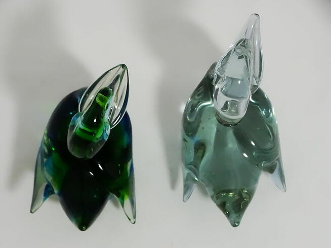 Dwie szklane figurki kaczek — jedna wielobarwna, druga w odc