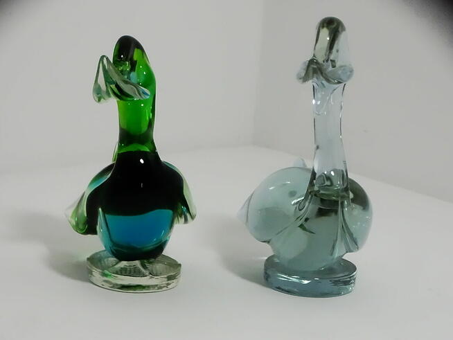 Dwie szklane figurki kaczek — jedna wielobarwna, druga w odc