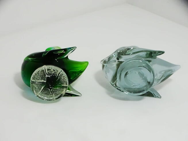 Dwie szklane figurki kaczek — jedna wielobarwna, druga w odc