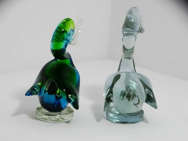 Dwie szklane figurki kaczek — jedna wielobarwna, druga w odc
